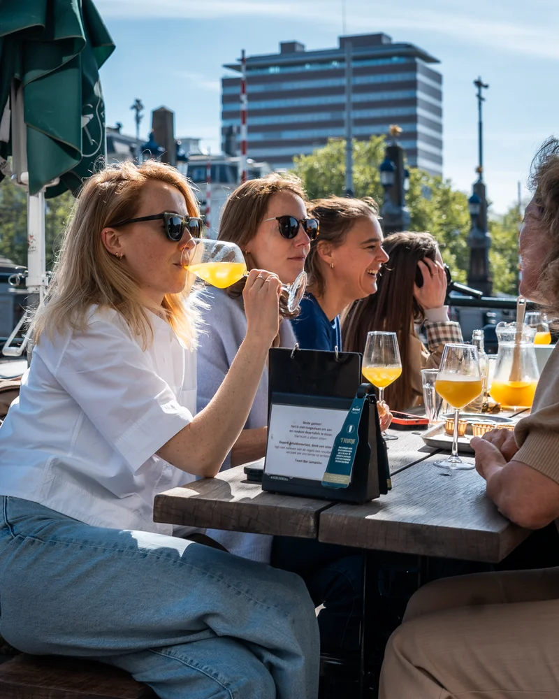 Gasten met wijn op het terras van Bar Lempicka bij de Amstel