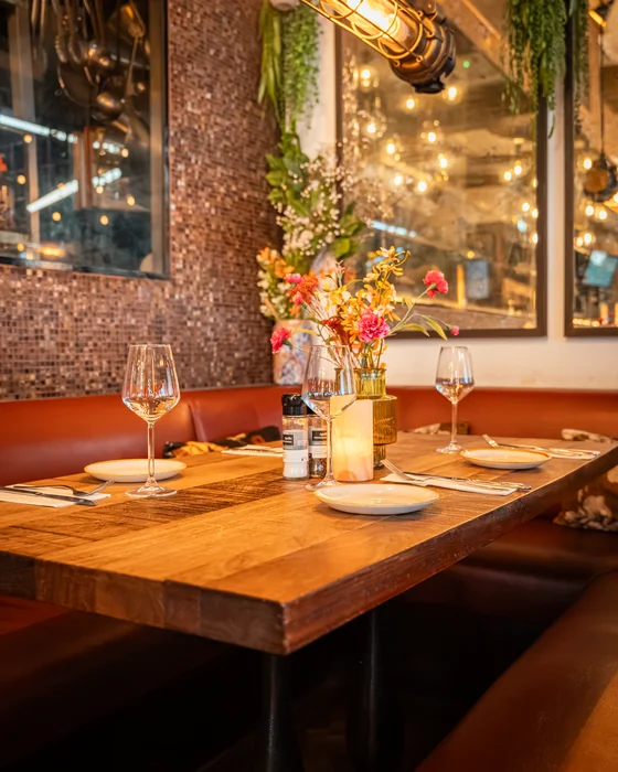 Gedekte tafel met bank en mozaïekwand in het interieur van Bar Lempicka
