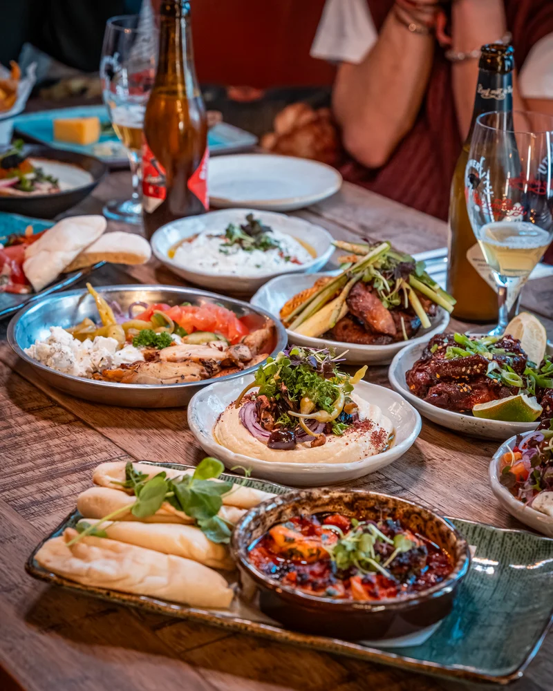 Houten tafel vol mediterrane gerechten om te delen bij Bar Lempicka Amsterdam