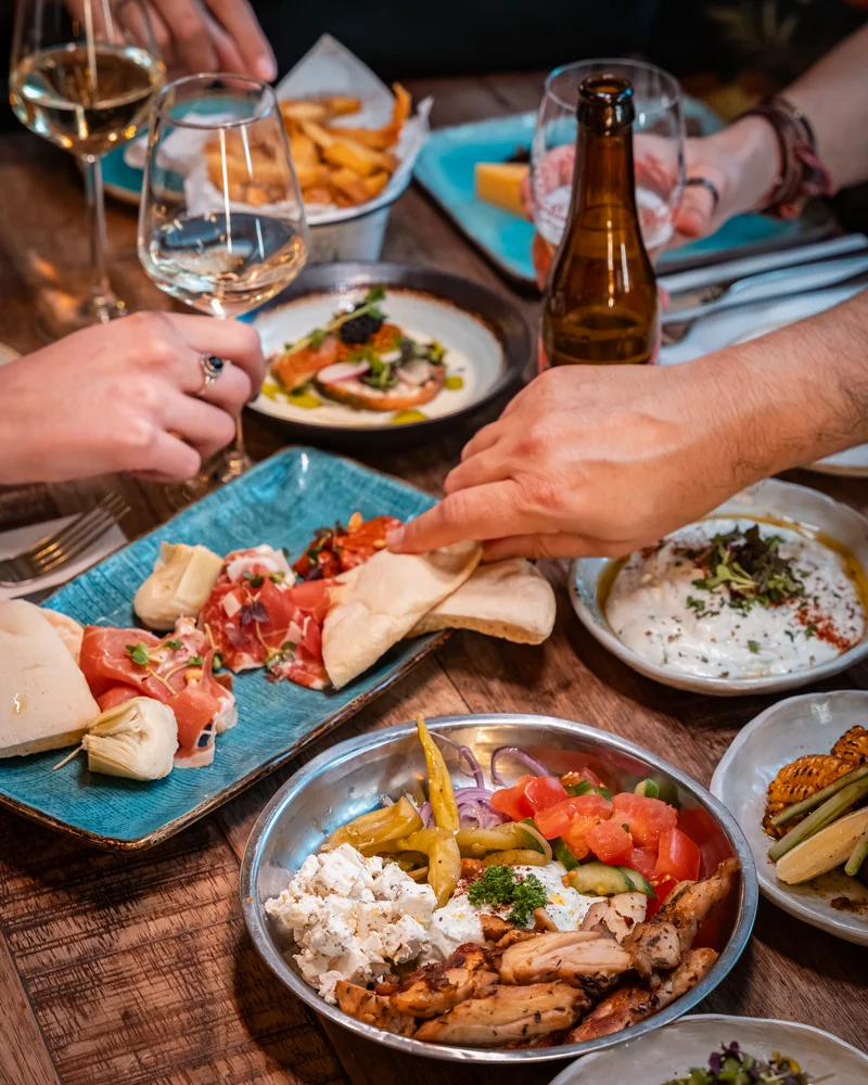 Gasten delen mezze van een blauwe schaal tijdens shared dining bij Bar Lempicka