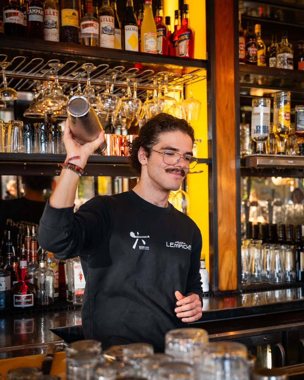 Barman aan het werk voor de verlichte flessenwand