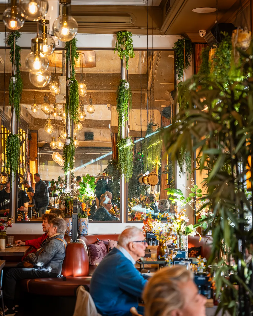 Gasten aan tafel onder de gloeilampen in de zaal