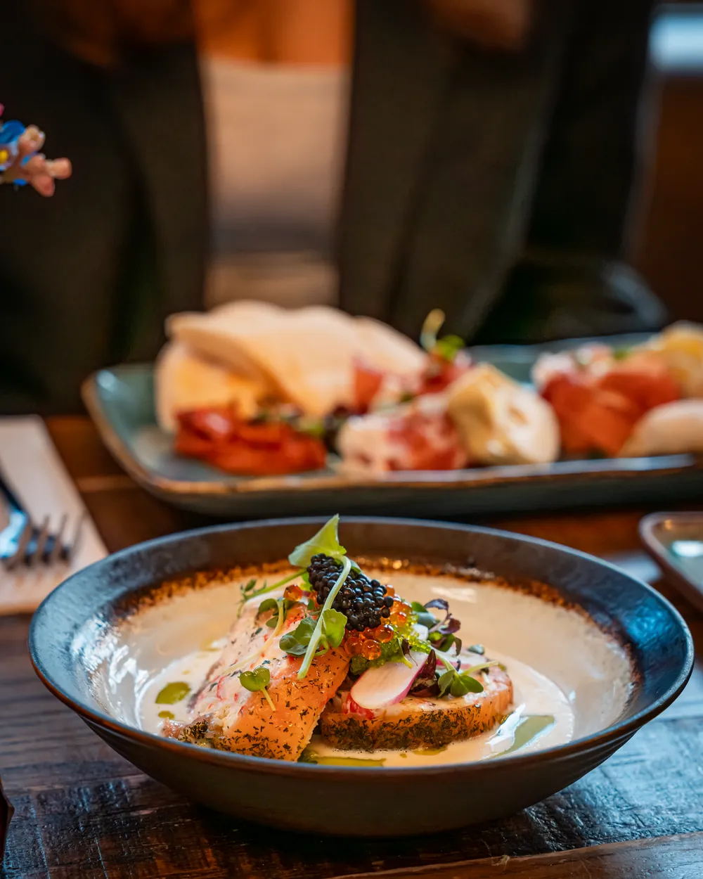 Zalmgerecht op tafel met vleesplank op de achtergrond