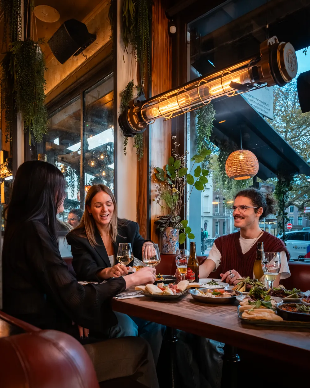 Drie gasten lachen aan een raamtafel