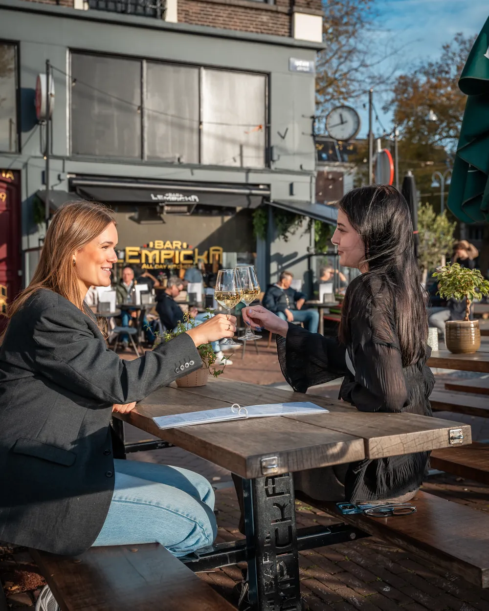 Gasten proosten op het terras voor de gevel van Bar Lempicka