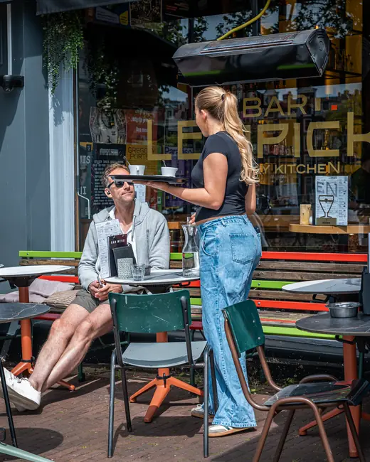 Medewerker brengt drankjes naar een gast op het terras van Bar Lempicka